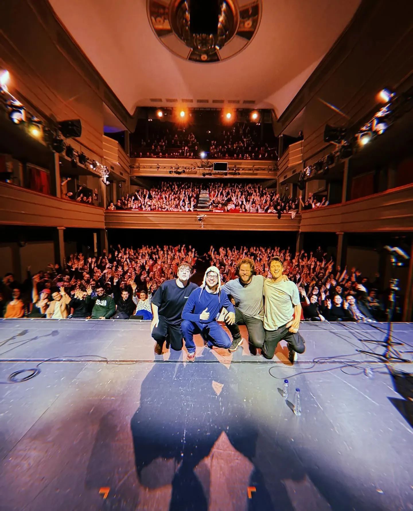 El equipo de Aislados posando en el escenario frente a un teatro lleno