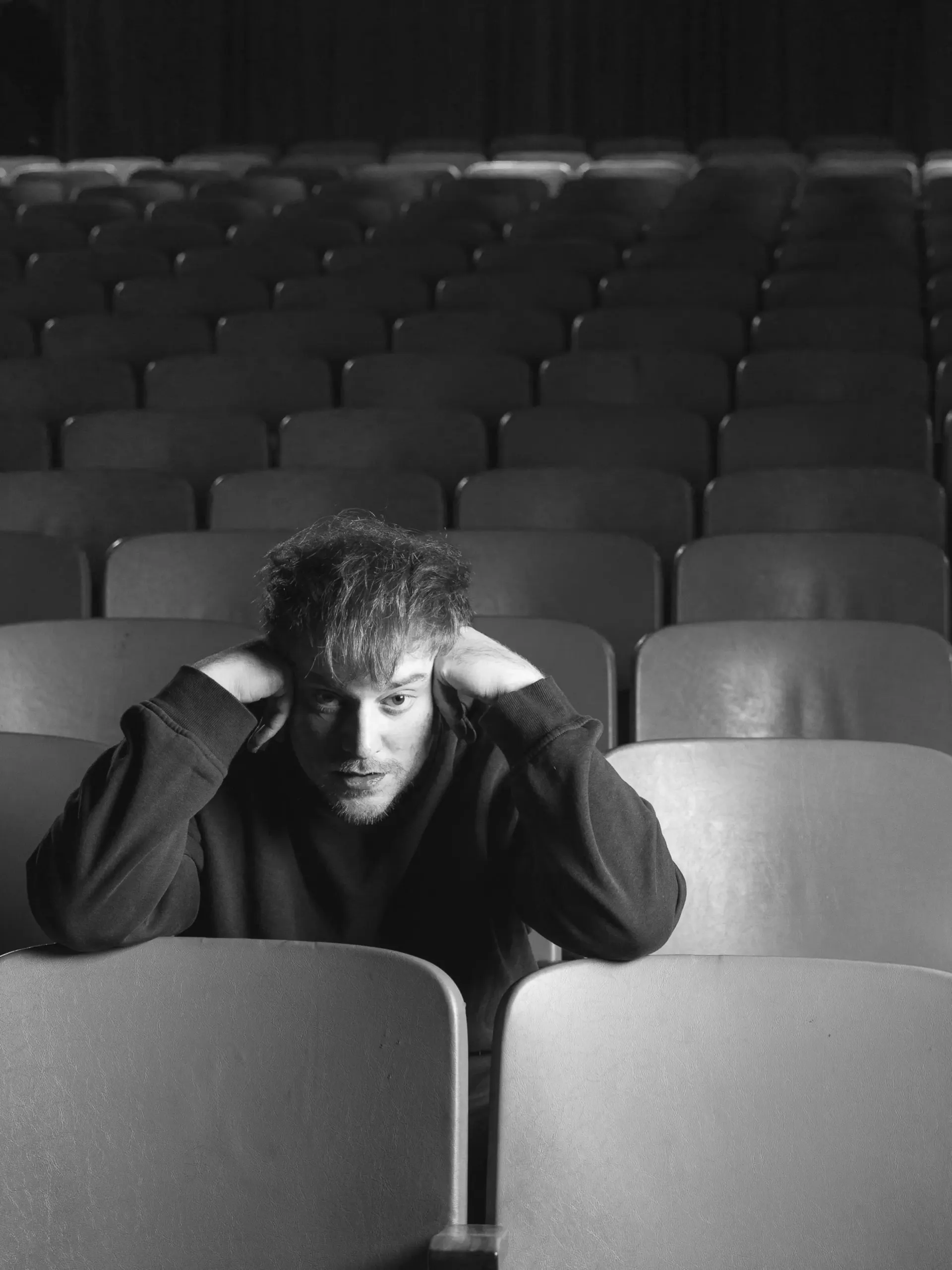 Lucas Lauriente sentado entre butacas vacías de un teatro